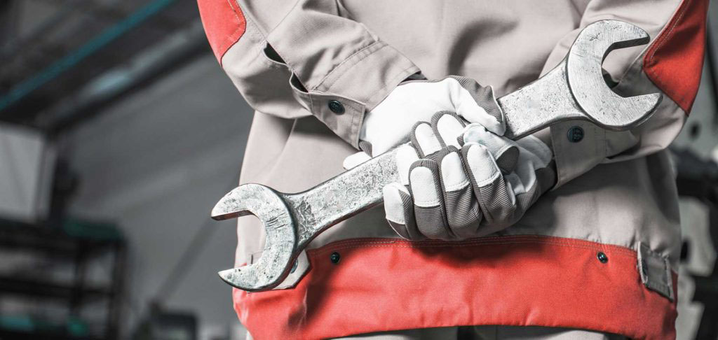 factory worker holding large wrench in factory